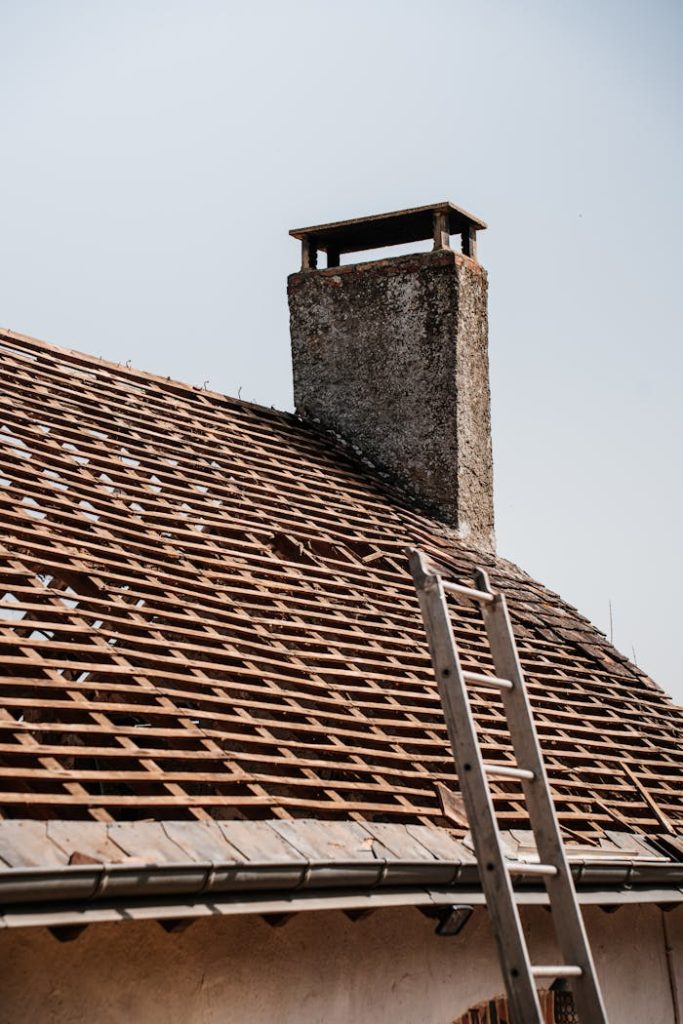 rustic-roof-renovation-with-chimney-and-ladder-31763534 A traditional rooftop under renovation with visible chimney and ladder.